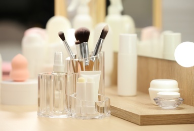 Photo of Organizer with cosmetic products and makeup accessories on dressing table indoors