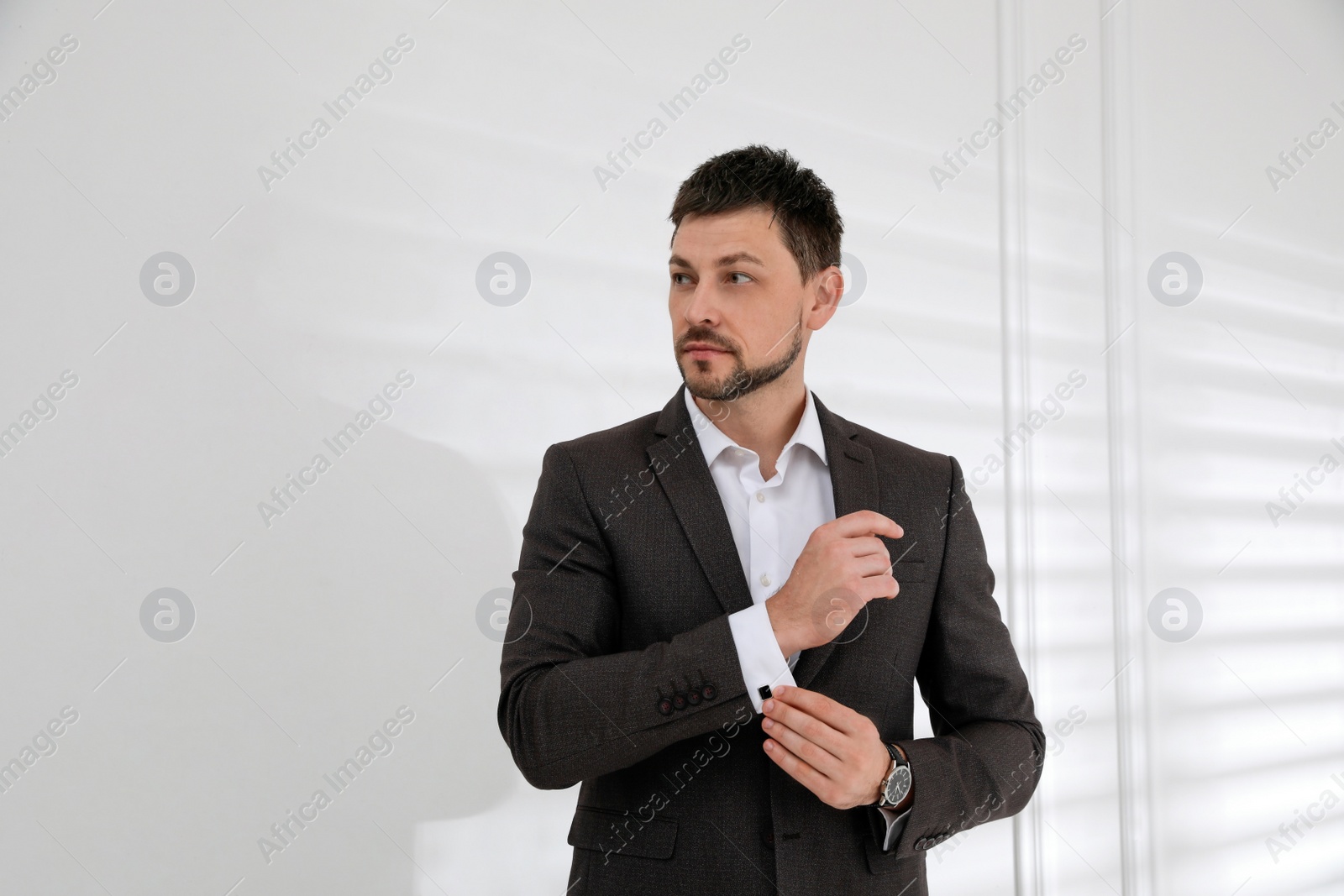 Photo of Man wearing stylish suit and cufflinks near white wall, space for text