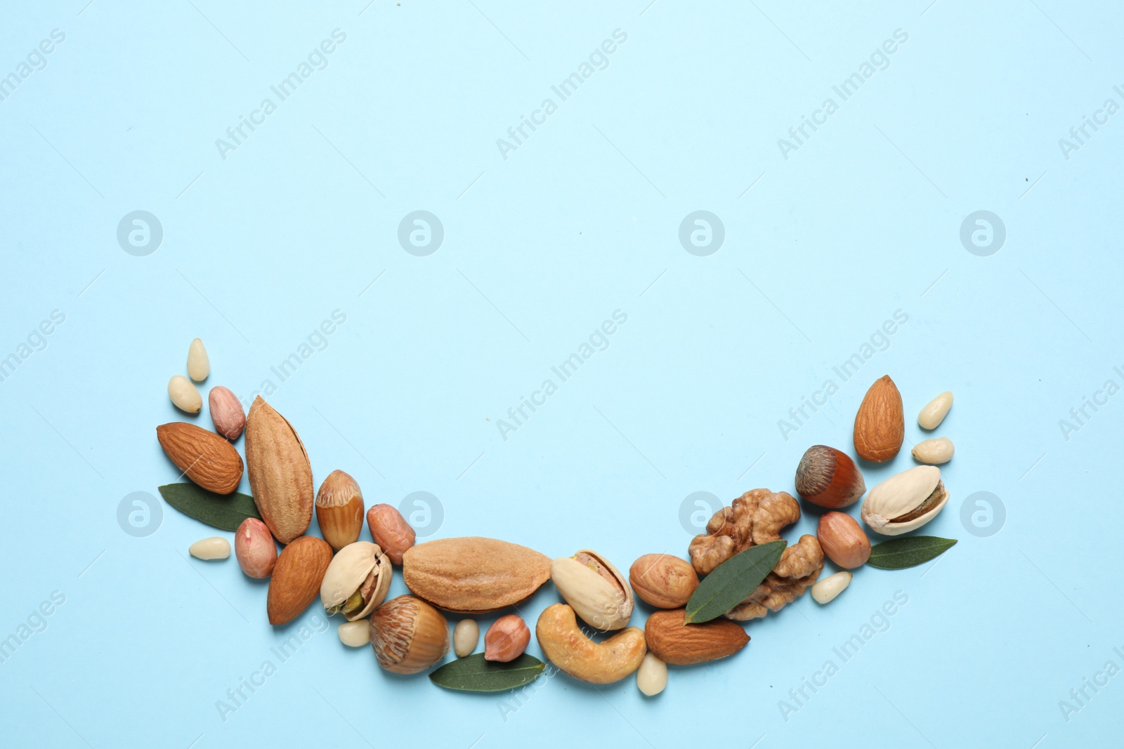 Photo of Different delicious nuts on light blue background, flat lay. Space for text