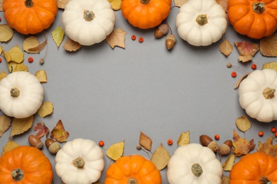 Photo of Frame made of different pumpkins, autumn leaves and acorns on grey background, flat lay. Space for text