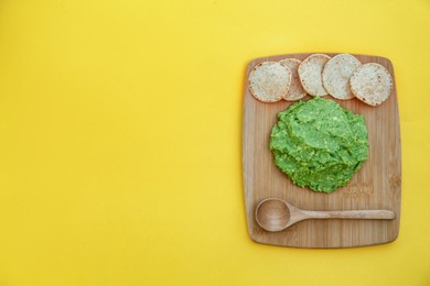 Photo of Delicious guacamole made of avocados and nachos on yellow background, top view. Space for text