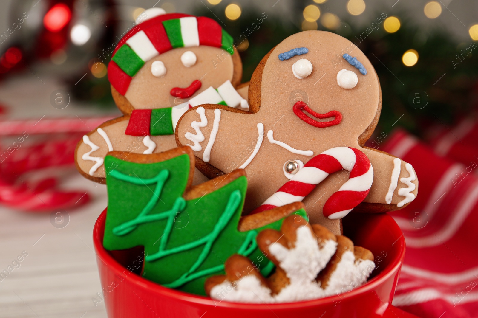 Photo of Delicious Christmas cookies in cup against blurred lights, closeup