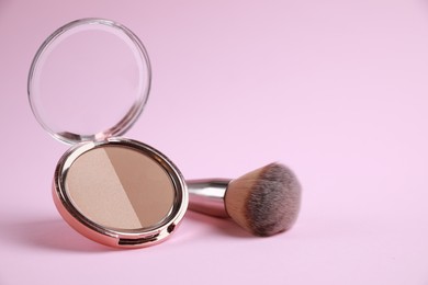 Face powder and brush on pink background, space for text
