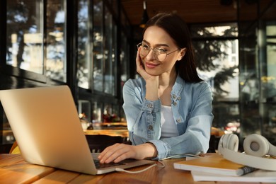 Photo of Young female student with laptop studying at table in cafe