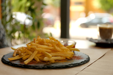 Photo of Delicious hot french fries with red sauce served on table