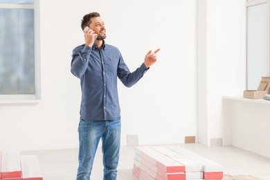 Photo of Man talking on phone in apartment during repair, space for text