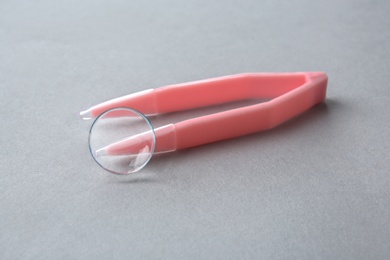 Tweezers with contact lens on light background