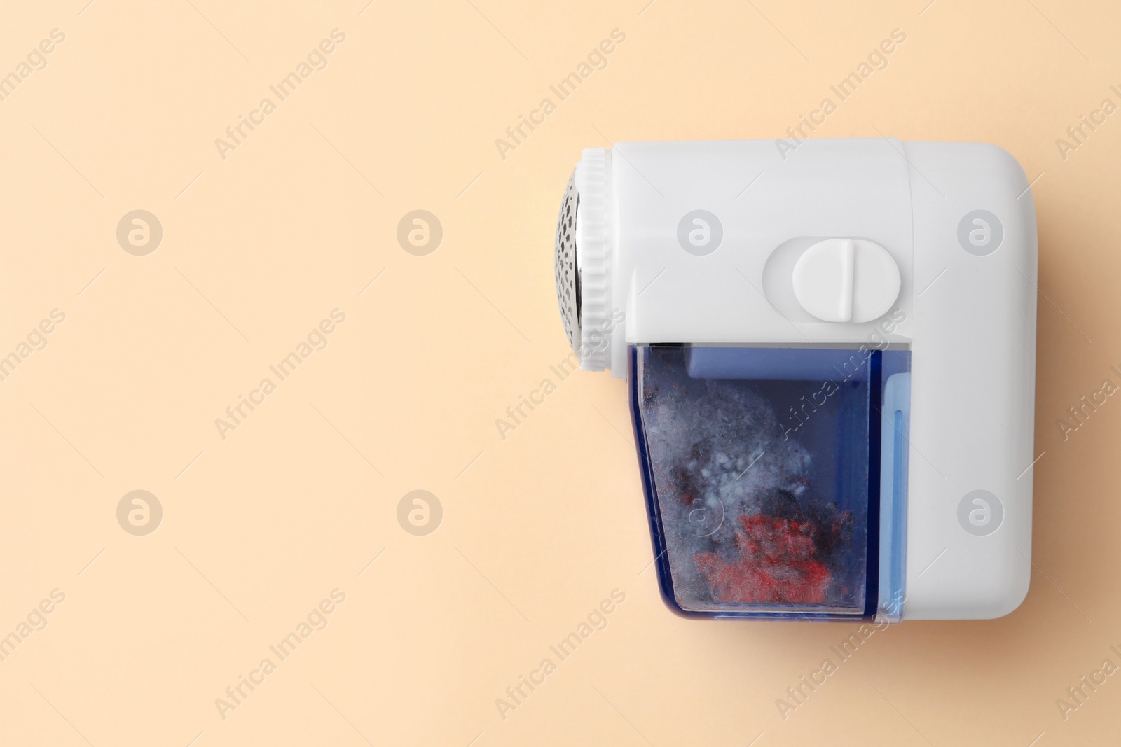 Photo of Modern fabric shaver with fuzz on beige background, top view. Space for text