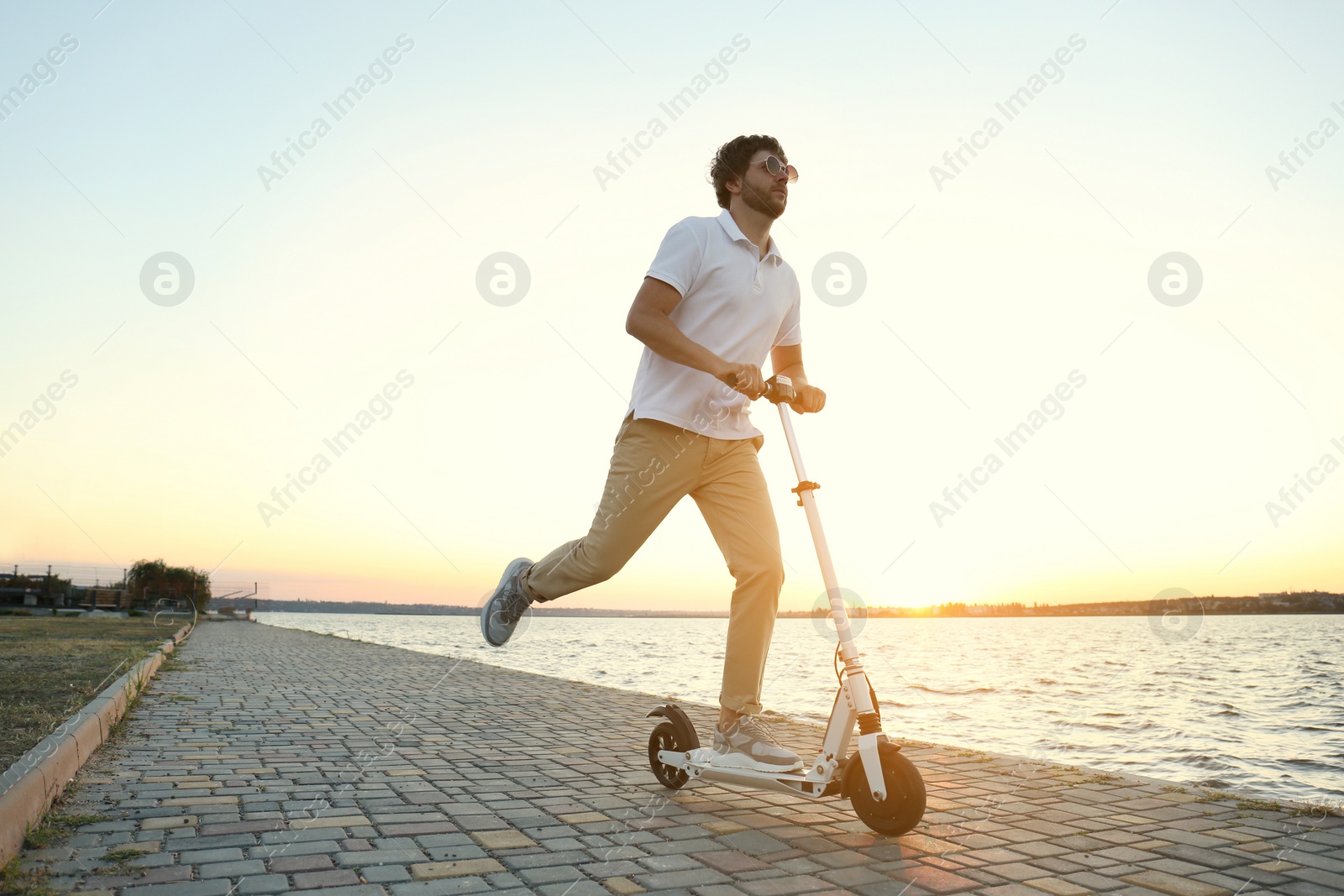 Photo of Man riding modern kick scooter along waterfront