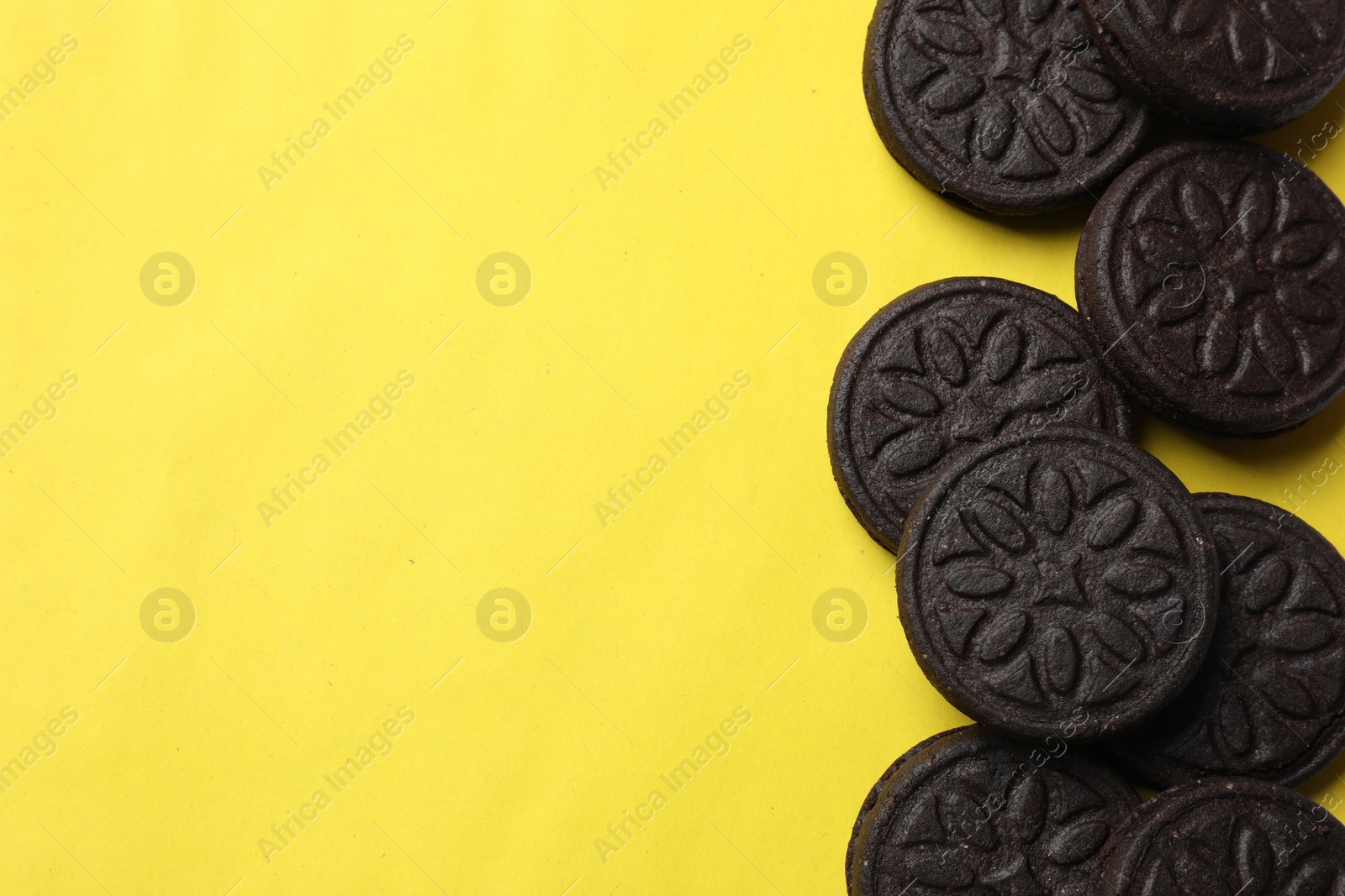 Photo of Tasty sweet sandwich cookies on yellow background, flat lay. Space for text