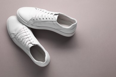 Photo of Pair of stylish white sneakers on grey background, top view. Space for text