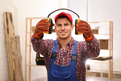 Photo of Worker holding safety headphones indoors, focus on hands. Hearing protection device