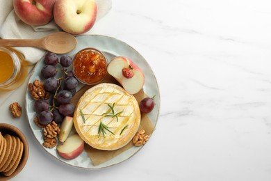 Photo of Tasty baked brie cheese served on white marble table, flat lay. Space for text