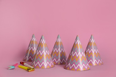 Colorful party hats and blowers on pink background