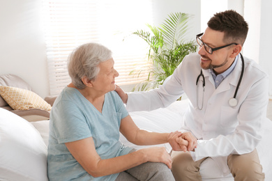 Photo of Doctor visiting senior patient in modern hospital