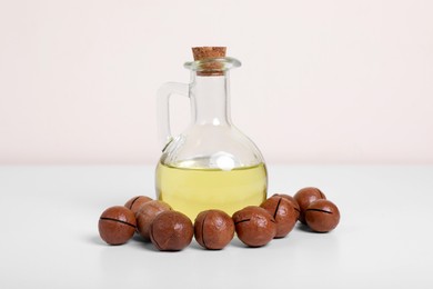 Photo of Delicious organic Macadamia nuts and natural oil on white background