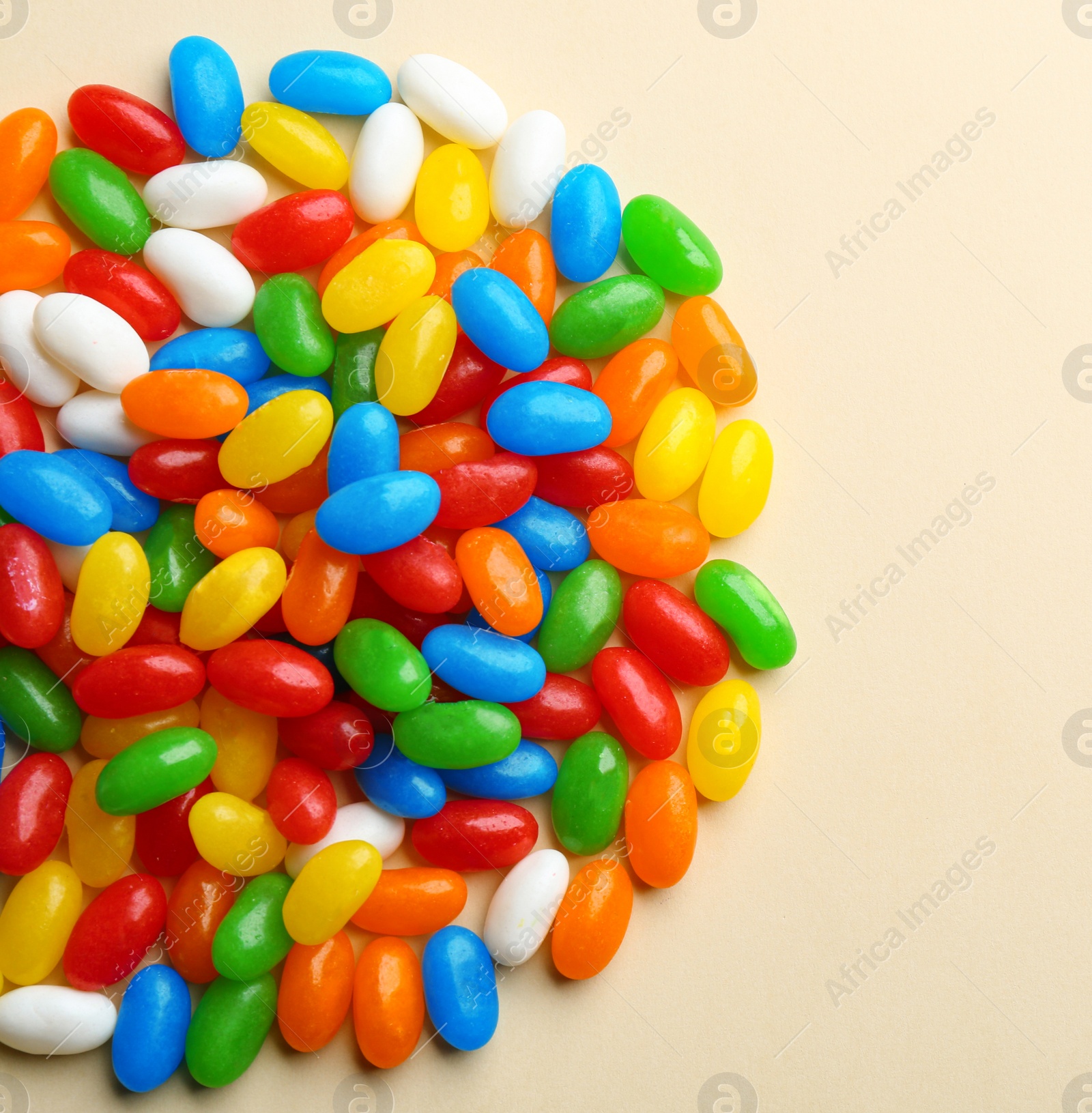 Photo of Pile of colorful jelly beans on beige background, flat lay. Space for text