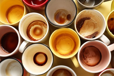 Photo of Many dirty cups after drinking coffee on yellow table, flat lay