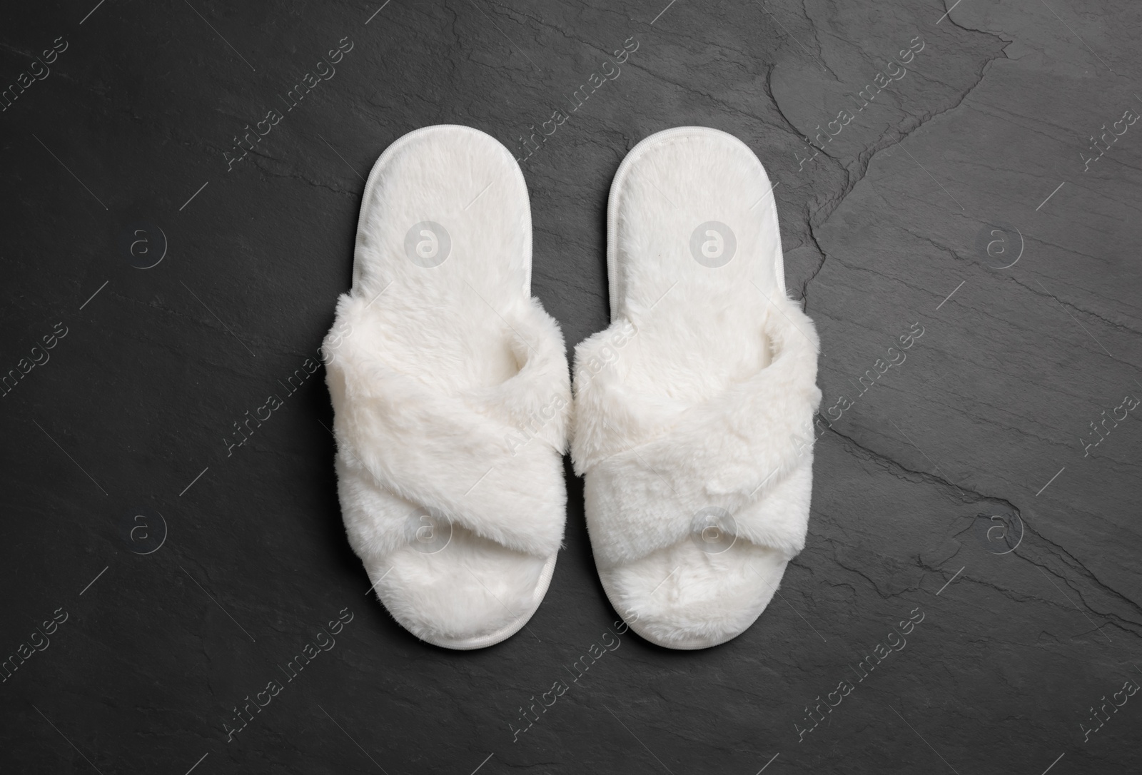 Photo of Pair of soft slippers on dark grey floor, top view