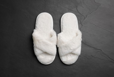 Photo of Pair of soft slippers on dark grey floor, top view