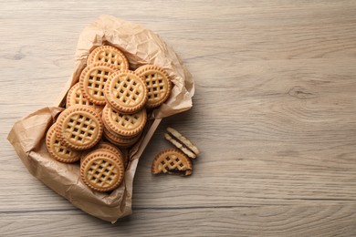 Photo of Tasty sandwich cookies with cream on wooden table, flat lay. Space for text