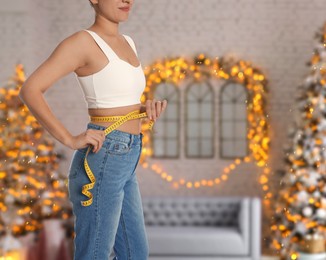 Woman measuring waist with tape in room decorated for Christmas, closeup