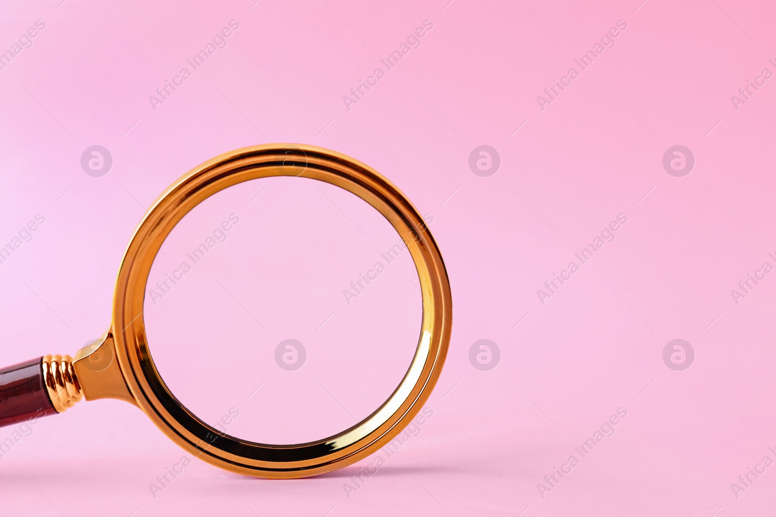 Photo of Magnifying glass with handle on pink background. Space for text