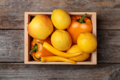 Crate full of fresh ripe fruits and vegetables on wooden background, top view