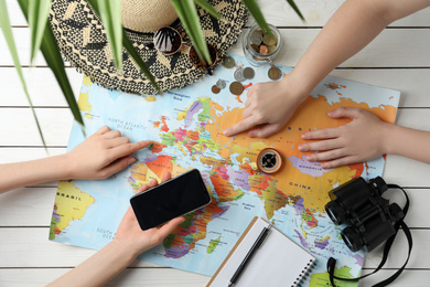 Photo of People with world map and accessories at table, top view. Travel during summer vacation