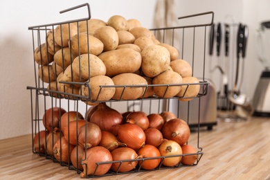 Photo of Container with potatoes and onions on wooden kitchen counter. Orderly storage