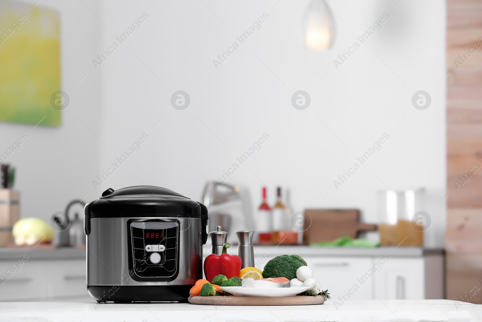 Photo of Modern multi cooker and products on table in kitchen. Space for text