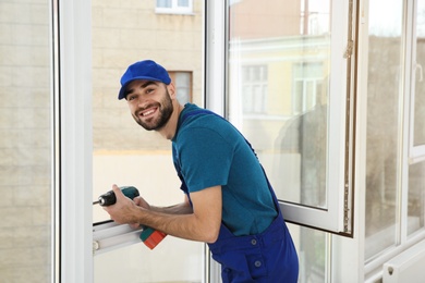 Construction worker using drill while installing window indoors