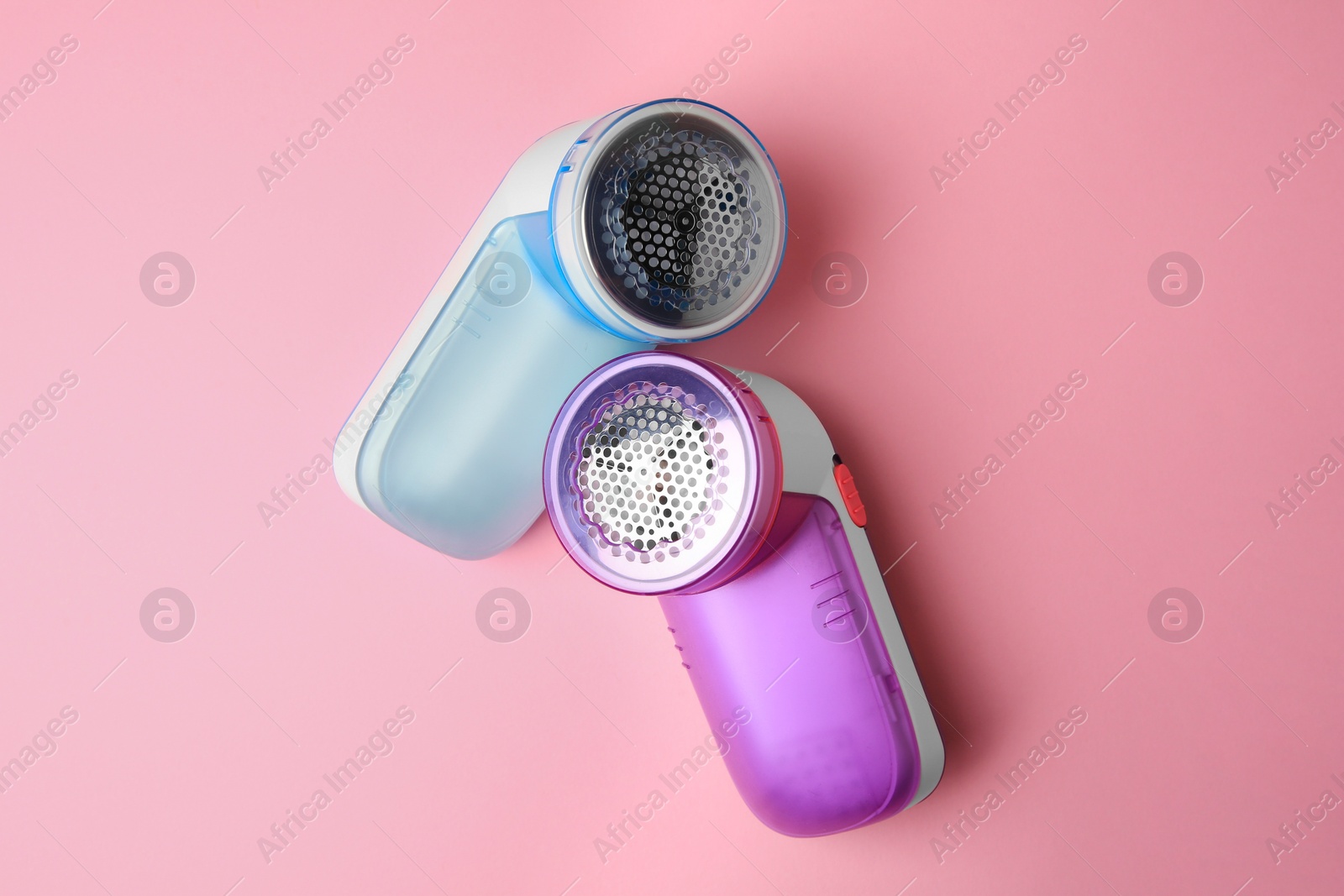 Photo of Modern fabric shavers on pink background, flat lay