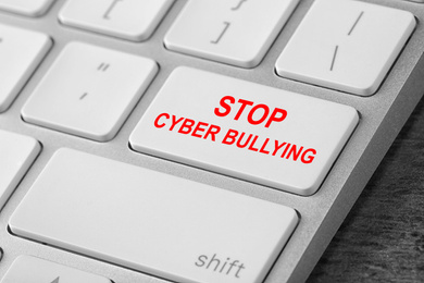 Image of Modern computer keyboard with phrase STOP CYBER BULLYING on white button, closeup