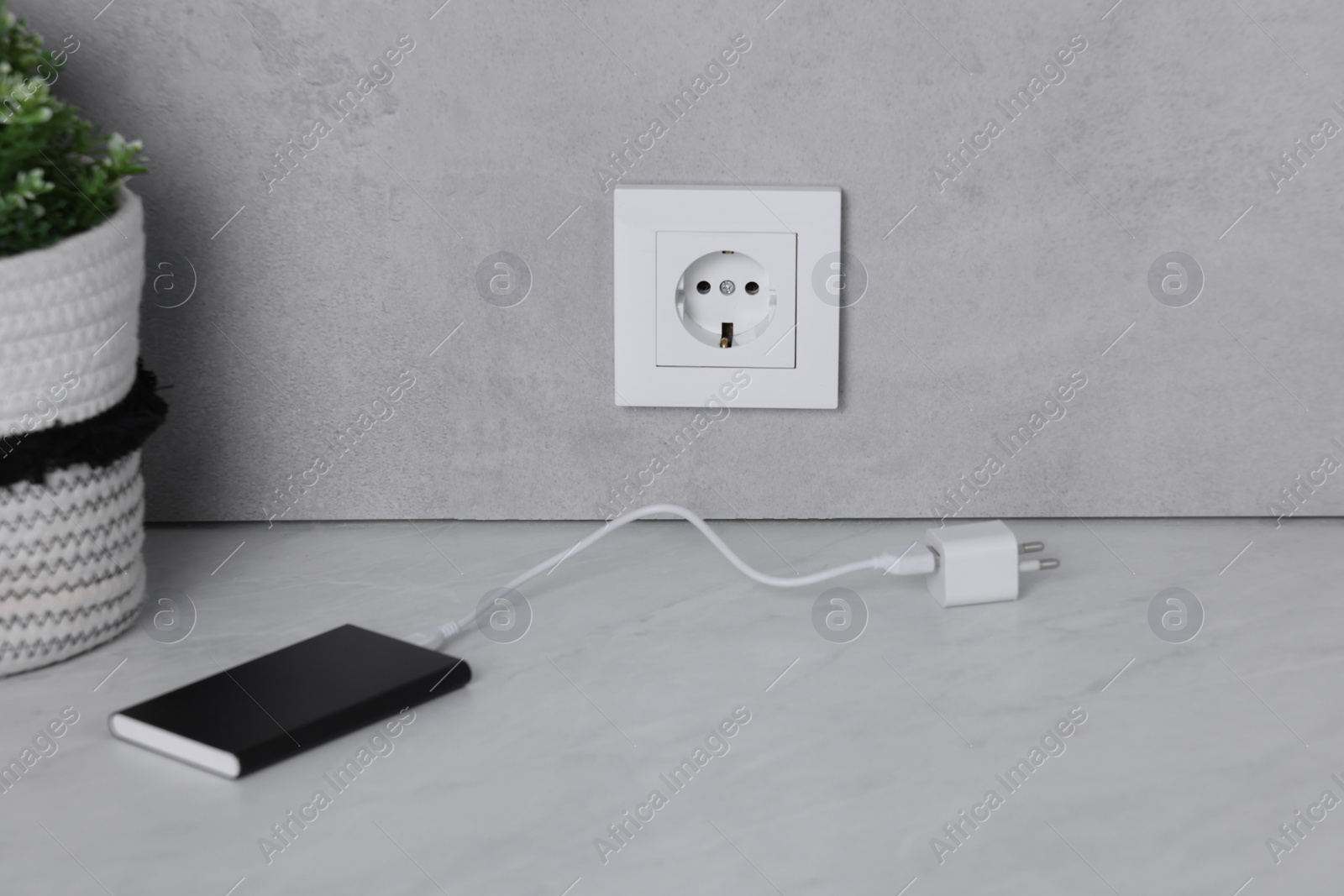 Photo of Electric socket and power bank on white table