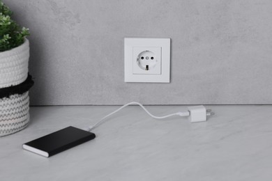 Electric socket and power bank on white table