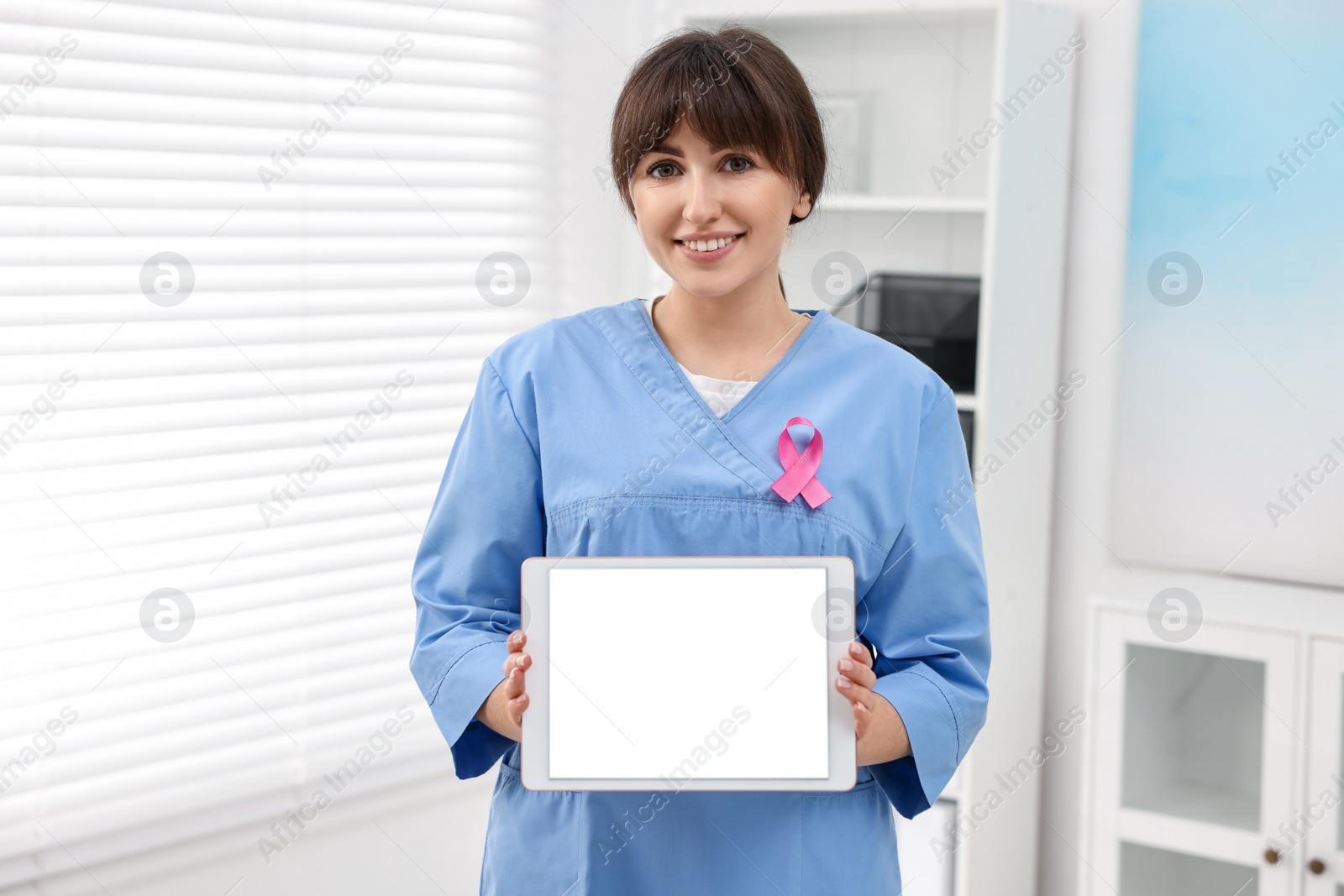 Photo of Mammologist with pink ribbon showing tablet in hospital. Breast cancer awareness