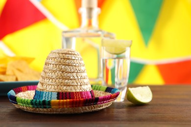 Photo of Mexican sombrero hat and tequila on wooden table. Space for text
