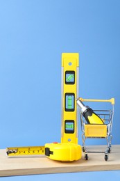 Photo of Small shopping cart with set of construction tools on light blue background