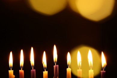 Hanukkah celebration. Burning candles on dark background with blurred lights