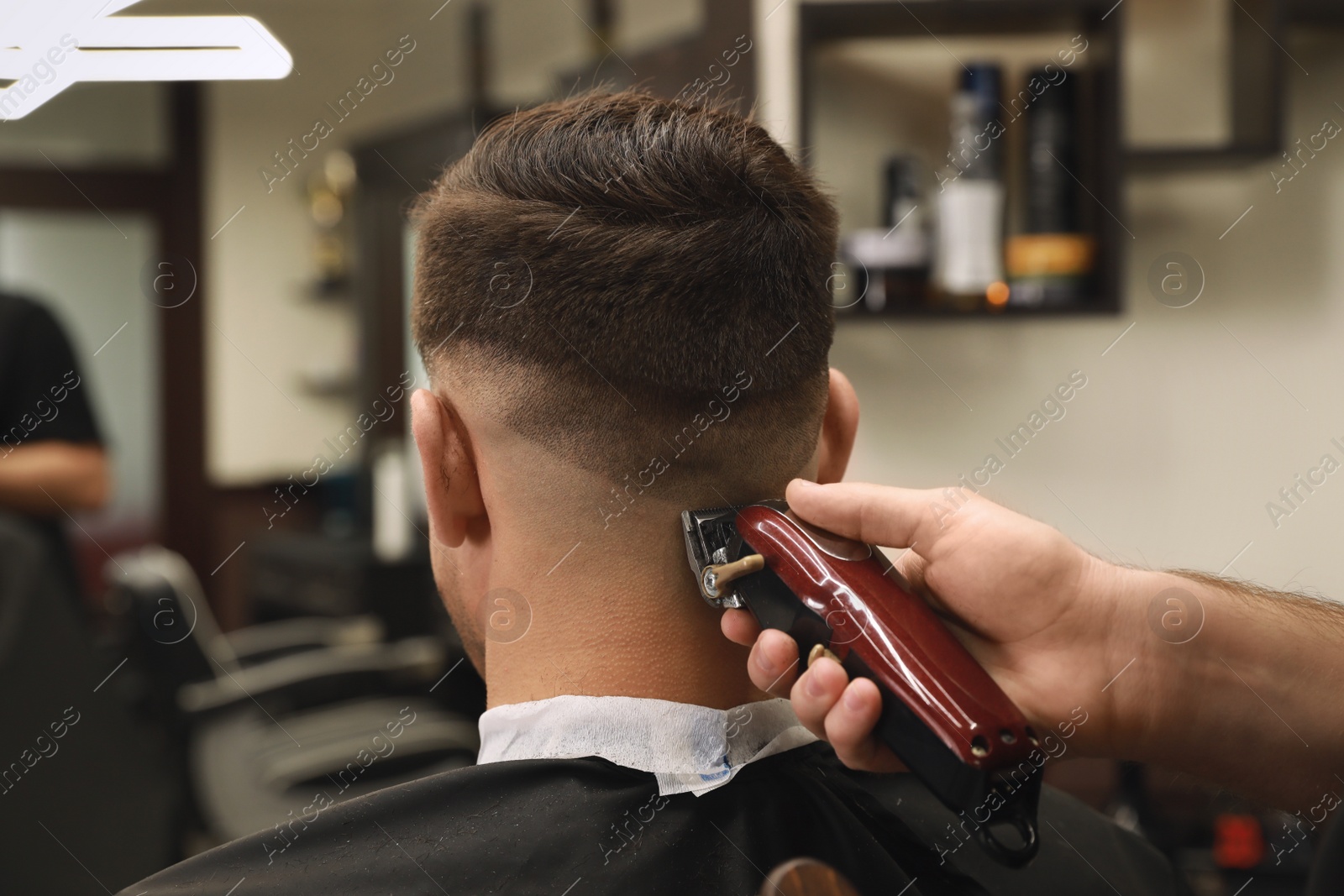 Photo of Professional hairdresser making stylish haircut in salon, back view