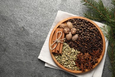 Different spices, nuts and fir branches on gray table, flat lay. Space for text