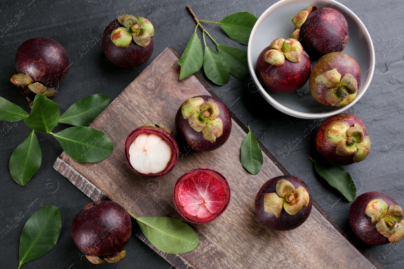 Photo of Fresh ripe mangosteen fruits on dark grey table, flat lay