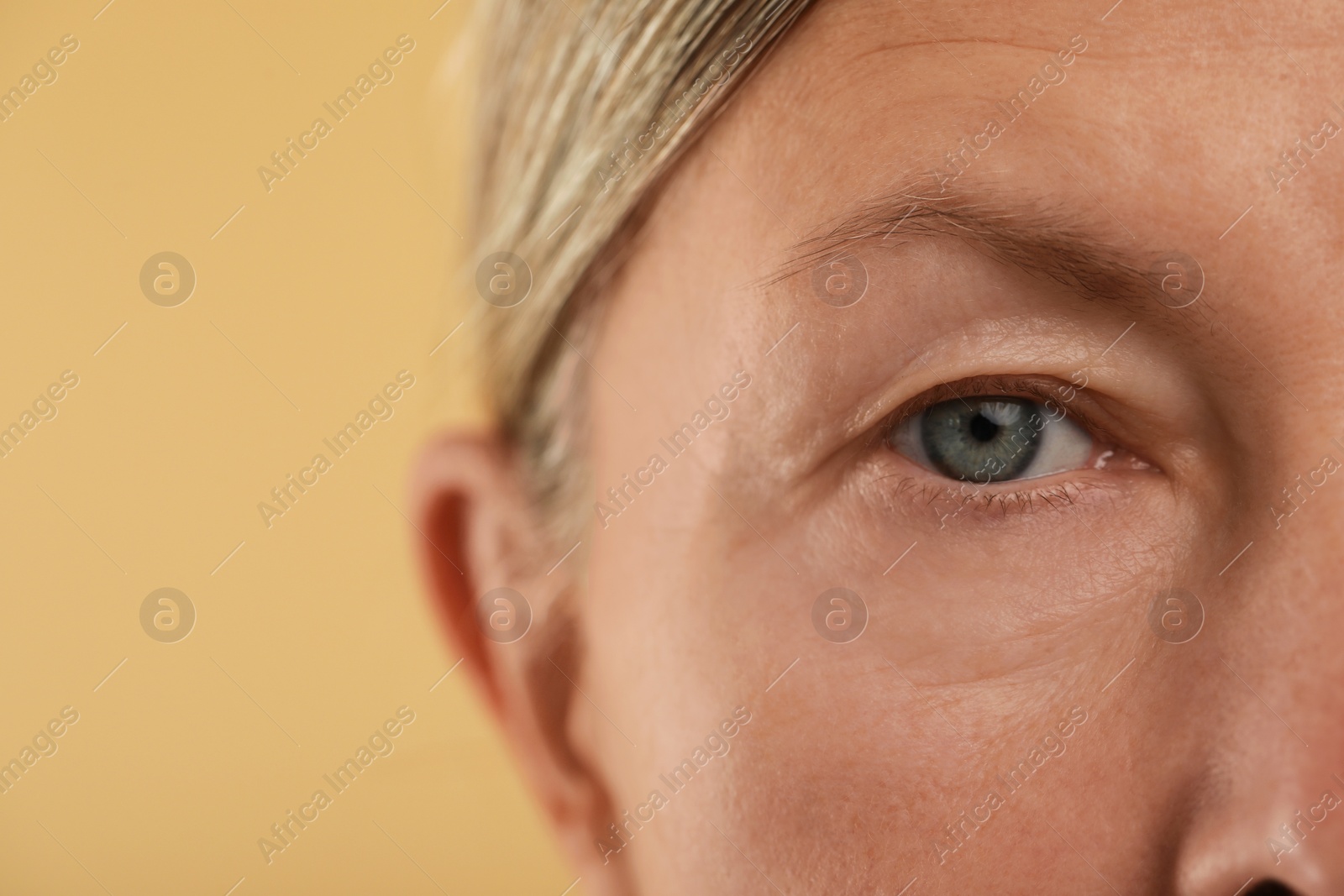 Photo of Woman with beautiful eyes on beige background, macro view. Space for text