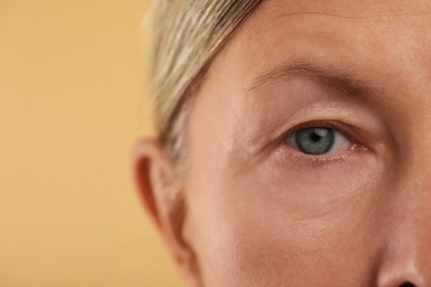 Woman with beautiful eyes on beige background, macro view. Space for text