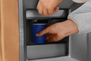 Photo of Woman taking paper cup with coffee from vending machine, closeup