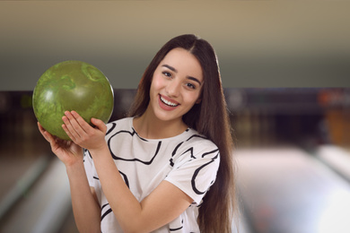 Photo of Young woman with ball in bowling club