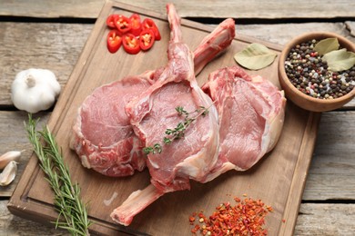 Photo of Fresh tomahawk beef cuts and spices on wooden table, above view