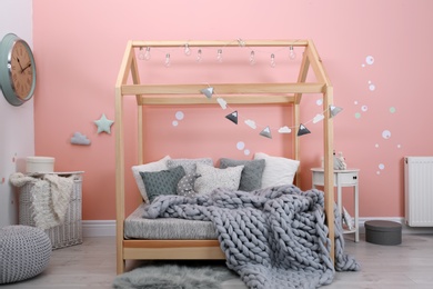 Photo of Child's room interior with comfortable bed and garland