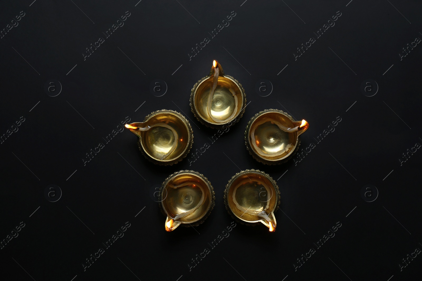 Photo of Lit diyas on dark background, flat lay. Diwali lamps